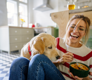Rapariga feliz a comer com o seu cão ao lado