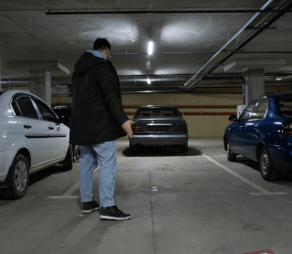 Homem na garagem a olhar para o seu carro