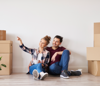 Casal sentado no chão da casa nova