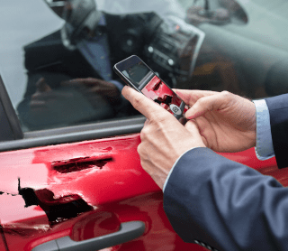 Homem a tirar fotografia ao seu carro partido