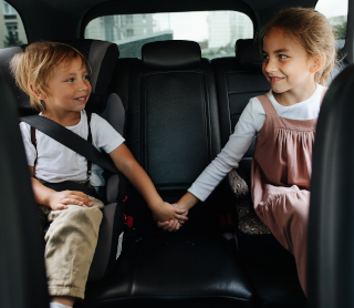 Duas crianças de mão dada no banco de trás do carro