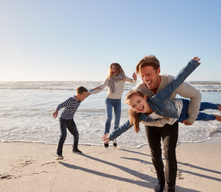 Família de pais e filhos a brincar na praia