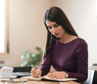 Mulher concentrada a escrever num caderno