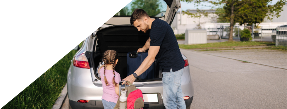 Pai com a filha a pôr malas de viagem no carro