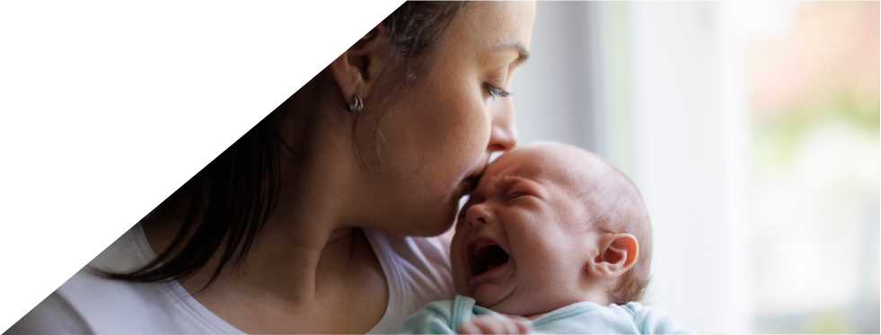 mãe a dar beijinho na testa de bebé a chorar