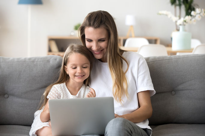 Mulher com a filha estão ao computador.