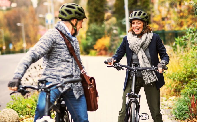 Casal senior passeia de bicicleta na cidade escolhida para evitar condições meteorológicas extremas.