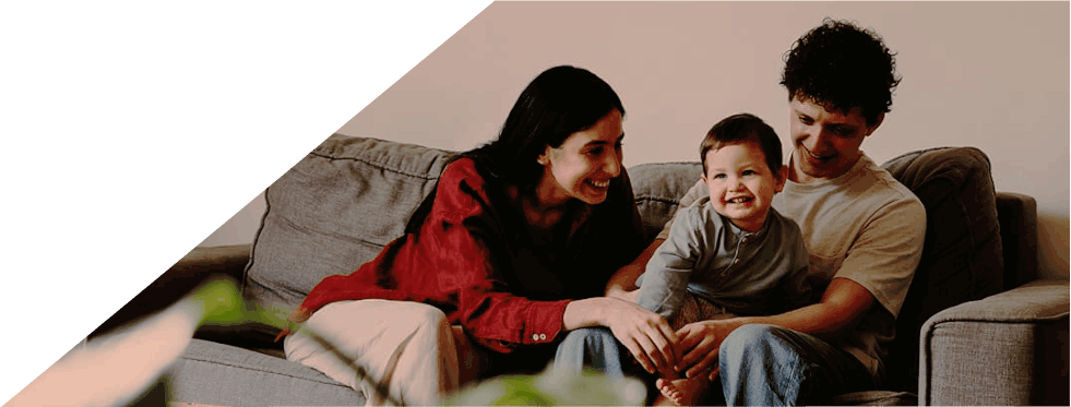 Família sorridente sentada num sofá na sala de estar.