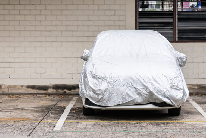Veículo coberto com capa de proteção branca para proteger o carro. 