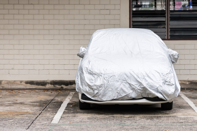 Veículo coberto com capa de proteção branca para proteger o carro.