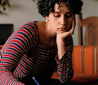 Mulher concentrada a escrever notas enquanto usa o computador portátil.