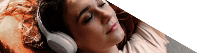 Mulher relaxa de olhos fechados enquanto ouve música com auscultadores.