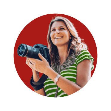 Rapariga sorridente, de máquina fotográfica na mão, em viagem