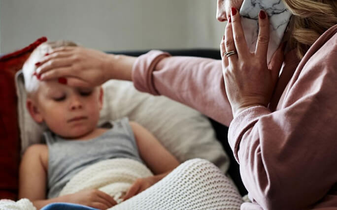 Mulher adulta cuida de criança com febre alta.