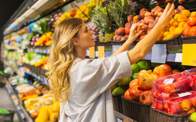 Mulher jovem escolhe legumes no supermercado, para manter os seus hábitos de vida saudável.