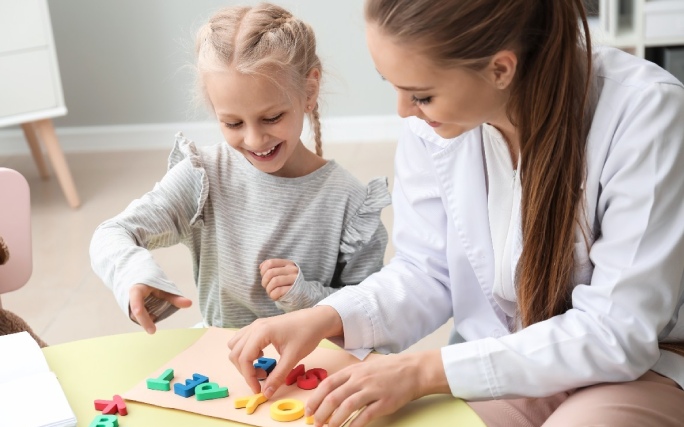 Uma terapeuta trabalha as letras e palavras com uma menina com dislexia.