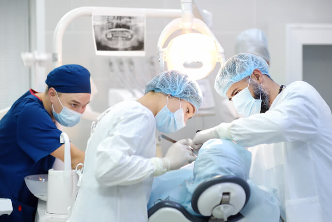 Equipa médica coloca implantes dentários num paciente, num consultório de um médico dentista.