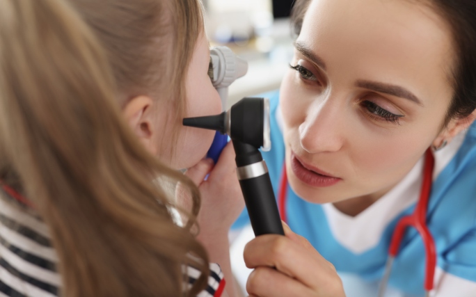Criança com dor de ouvido a ser examinada por um médico.