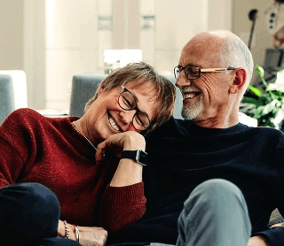 Casal maduro sorrindo e relaxando juntos em um sofá em casa.