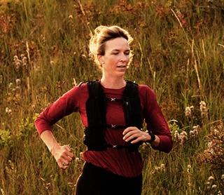 Mulher a correr num trilho ao ar livre ao pôr do sol.