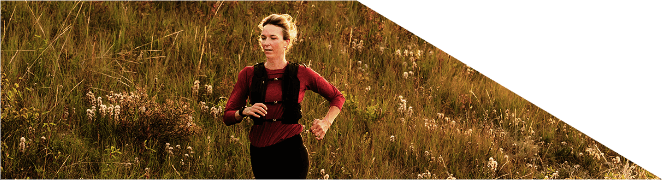 Mulher a correr num trilho ao ar livre ao pôr do sol.