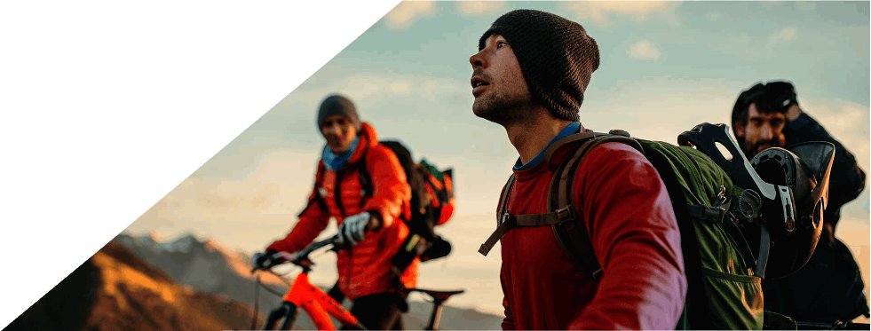Grupo de ciclistas de montanha a observar a paisagem ao pôr do sol.