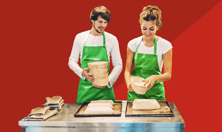 Homem e mulher com aventais verdes a distribuir cestos em tabuleiros.