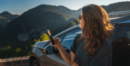 Jovem feliz encostada a um carro, a escolher seguro automóvel novo.